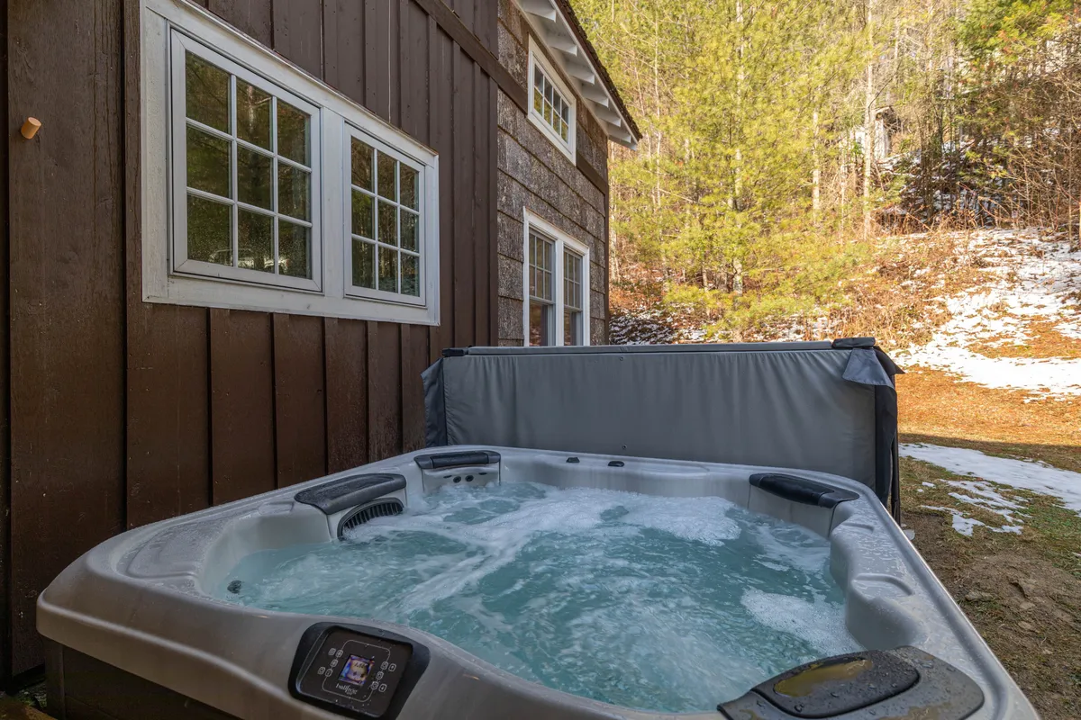 This image features a tranquil hot tub set against a wooden wall with windows looking out onto the natural surroundings. The scene captures the peaceful ambiance of the outdoor space, ideal for relaxation after a productive work session. The integration of the hot tub with the outdoors reflects the seamless transition from work to leisure mentioned in the section.